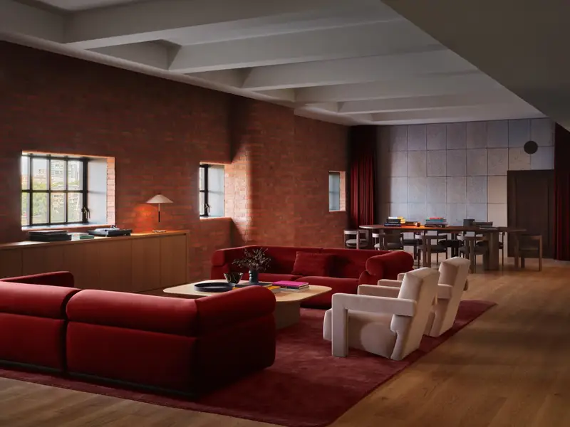 A greenroom in the Apple Music Radio studios: red sofas on a red rug, brick walls, a turntable on the sideboard