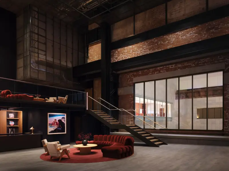 The foyer of Apple Music Hall: a red velvet sofa and a staircase under exposed brick and steel