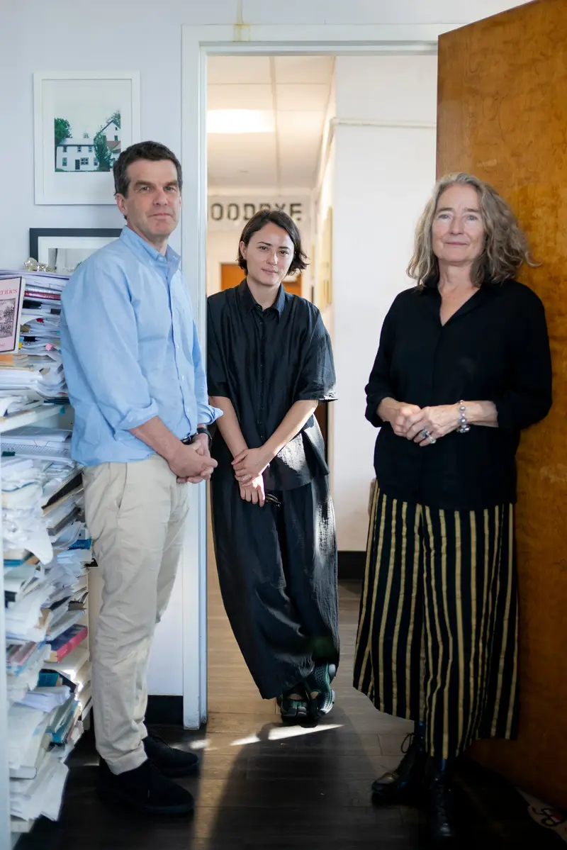 Declan Spring, Mieke Chew and Barbara Epler of New Directions, standing in a doorway of their book-stacked office